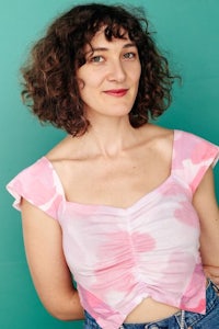 a woman in a pink top and jeans posing for a photo